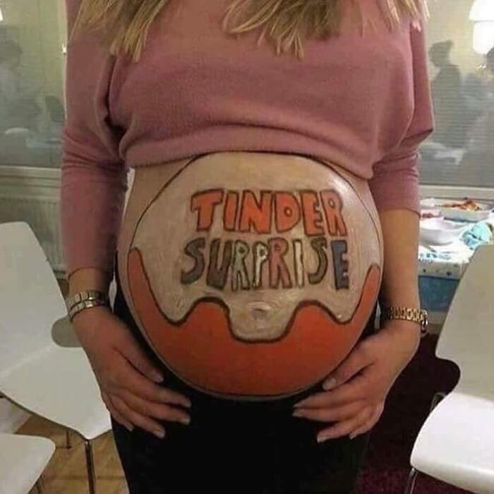 A pregnant woman's belly painted to resemble a Kinder Surprise egg, with the text TINDER SURPRISE.