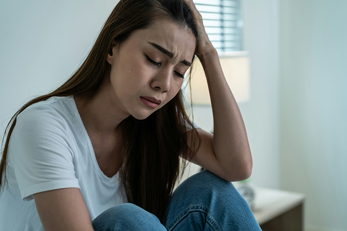A woman crying, looking at her husband's old pictures with his ex, feeling sad and hurt. A woman crying, looking at her husband's old pictures with his ex, feeling sad and hurt.
