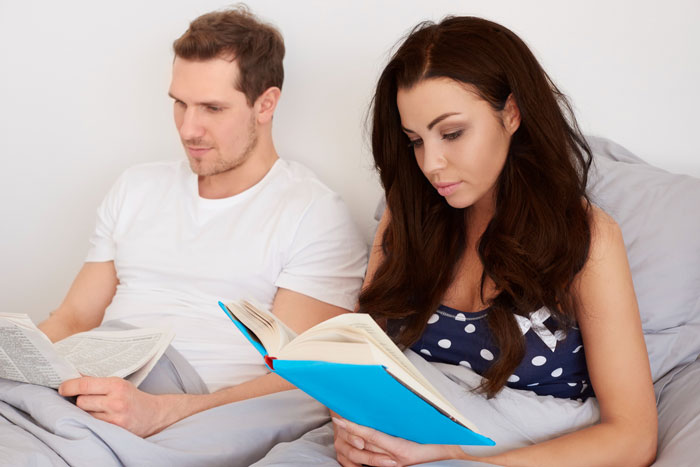 Man and pregnant wife in bed reading, a story about cheating and manipulation. Man and pregnant wife in bed reading, a story about cheating and manipulation.