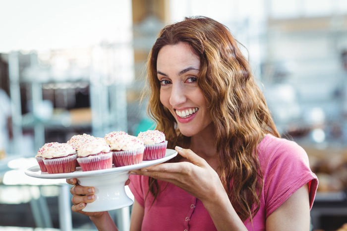 A woman smiling while holding a plate of cupcakes. The image relates to a guy who cheats on his pregnant wife. A woman smiling while holding a plate of cupcakes. The image relates to a guy who cheats on his pregnant wife.