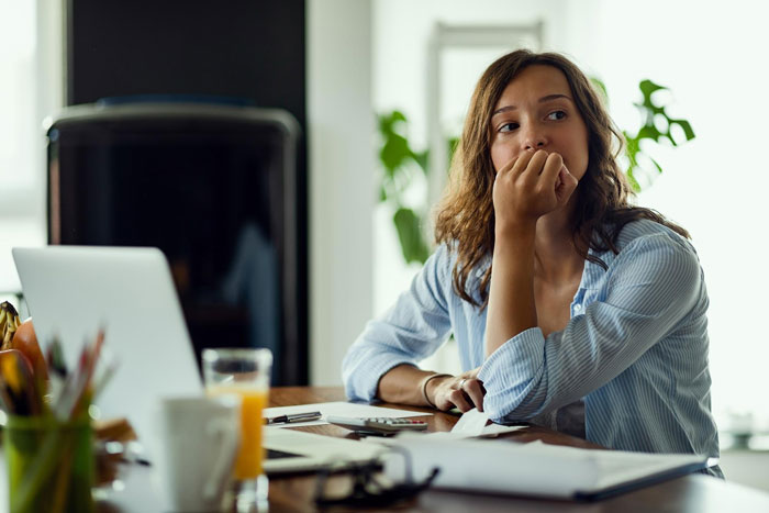 A pregnant wife looking worried while sitting at a table with a laptop, reflecting on her husband cheating. A pregnant wife looking worried while sitting at a table with a laptop, reflecting on her husband cheating.