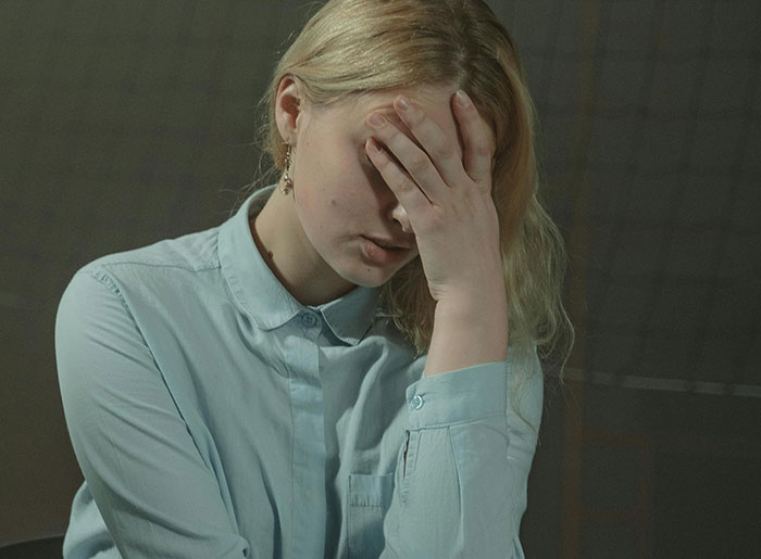 A distraught woman, head in her hand, after finding out her husband's true identity and asking for advice.