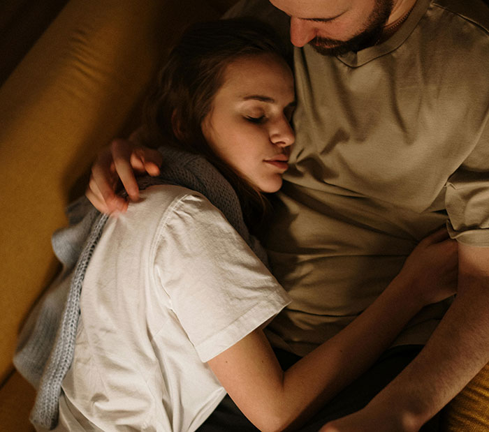 A woman rests her head on her husband's chest, looking sad and vulnerable, as she realizes she has no idea who her husband really is.