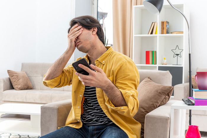 Young man frustrated while looking at his phone, reacting to his Mom tracking down $6K and asking for a $3K finder's fee. Young man frustrated while looking at his phone, reacting to his Mom tracking down $6K and asking for a $3K finder's fee.