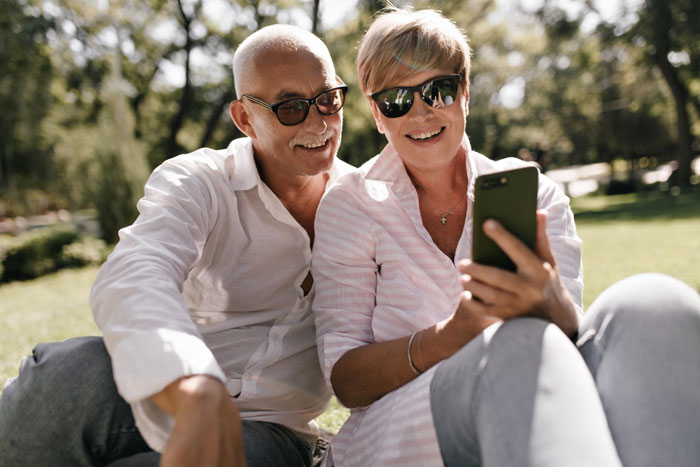 A happy couple sits on grass, enjoying their time together, perhaps discussing a son's long-lost $6K or a finder's fee. A happy couple sits on grass, enjoying their time together, perhaps discussing a son's long-lost $6K or a finder's fee.