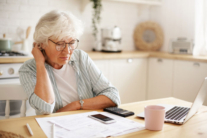 A thoughtful mom calculating finances in her kitchen, contemplating her son's long-lost money and finder's fee. A thoughtful mom calculating finances in her kitchen, contemplating her son's long-lost money and finder's fee.