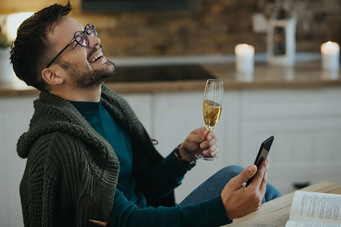 Man laughing, holding a phone and a glass of champagne, deciding to donate a kidney to his BIL. Man laughing, holding a phone and a glass of champagne, deciding to donate a kidney to his BIL.