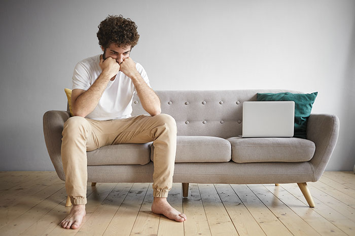 A man on a sofa looking upset, reflecting on changing his mind about donating a kidney. A man on a sofa looking upset, reflecting on changing his mind about donating a kidney.
