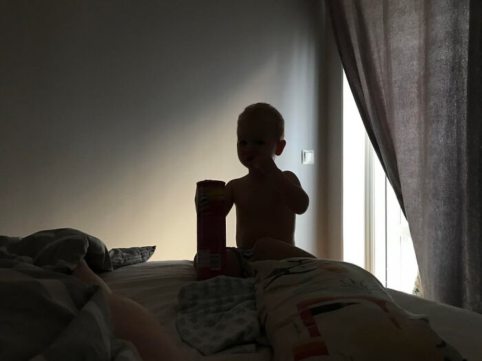 A silhouetted child sitting on a bed, holding a container, a moment that could make parents terrified.