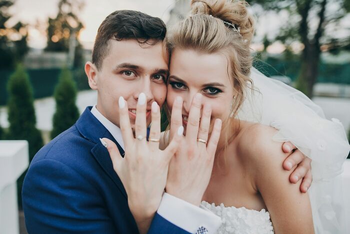 A happy couple showing off their wedding rings, a clever image implying identical twin chaos or a twin theme.