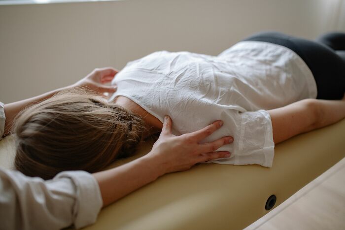 A person lying face down on a massage table receiving a back massage, experiencing pure chaos.