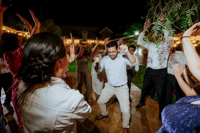 A group of identical twin wedding guests dancing at an outdoor reception, creating pure chaos.