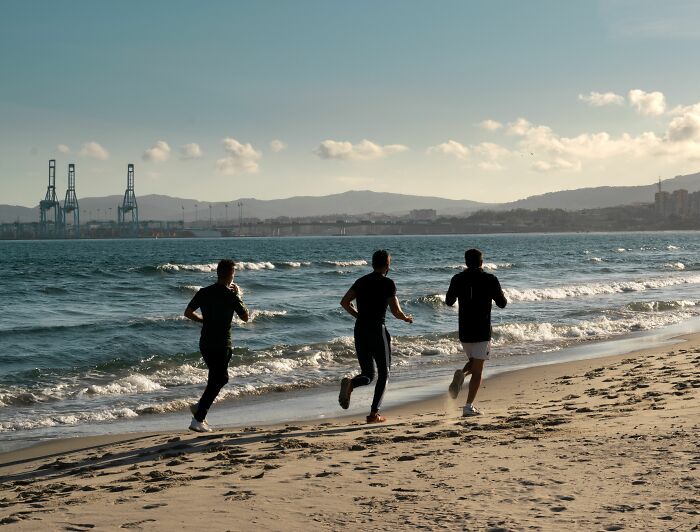 Three men run on a beach at sunset, showing the chaos of identical twin workouts.