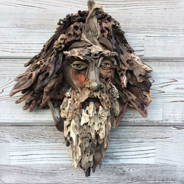 A stunning sculpture of a man's face with a beard and hair made from collected pieces of wood.