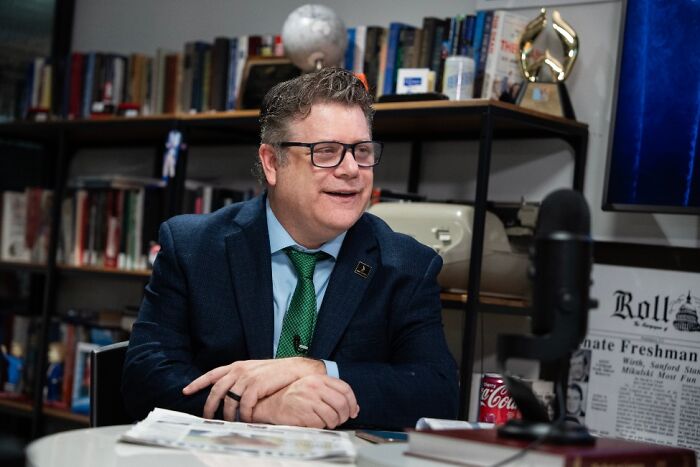 Hollywood Star in a $3 Billion Franchise; a man in glasses and a suit sitting at a desk with a microphone.