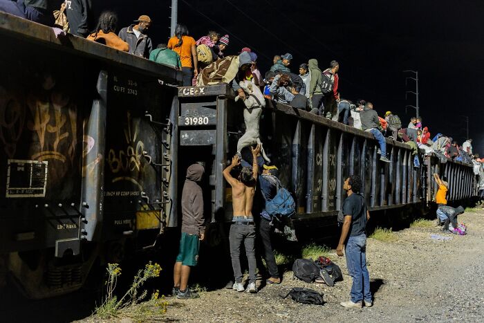 Remarkable color photo of people climbing onto a train car at night.