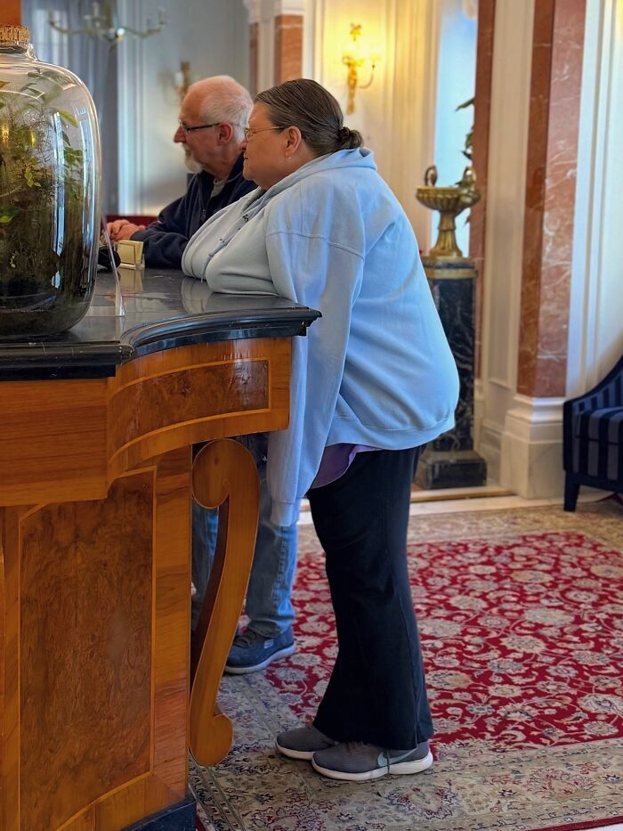 Photographer captures perfectly timed coincidences of people leaning over a counter in a fancy interior.