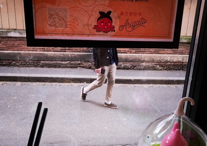 A perfectly timed street photo through a window showing a person walking on the street, revealing extraordinary moments.