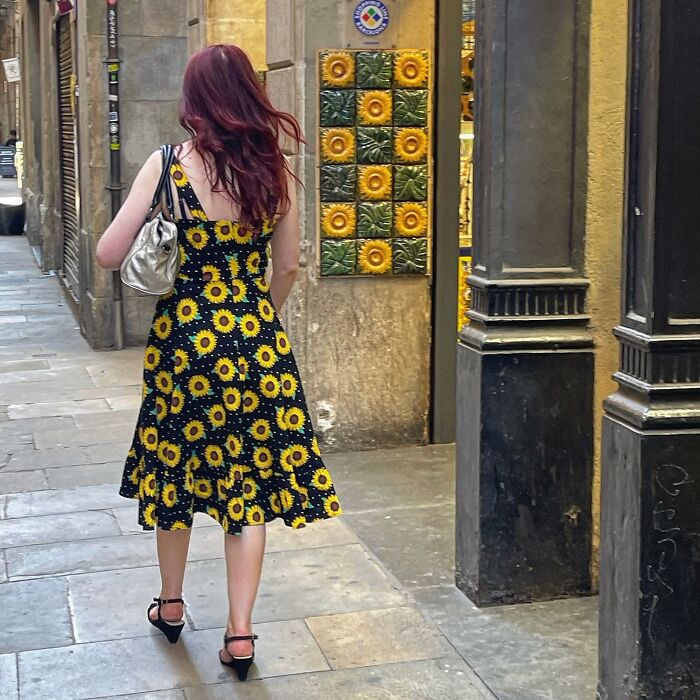 Photographer captures perfectly timed coincidences of a woman in a sunflower dress walking past tiled walls in Barcelona.
