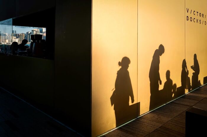 Street coincidence: Shadows of people lined up against a golden wall in Edas Wong's photo.