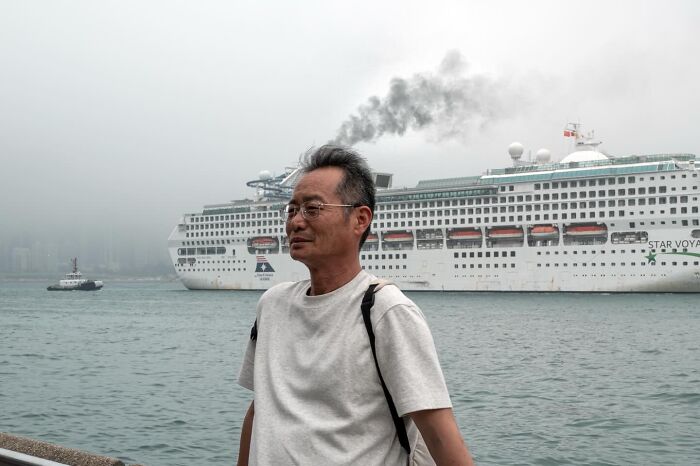 Street coincidence: A man stands in front of a cruise ship emitting smoke, captured by Edas Wong.