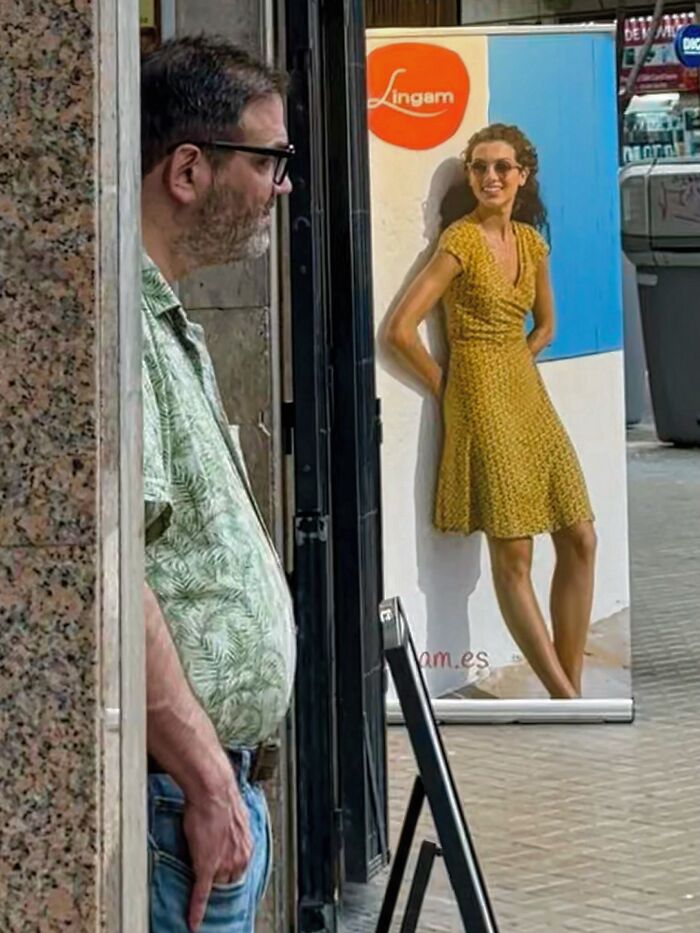 A photographer captures perfectly timed coincidences in Barcelona: a man looking at a banner of a smiling woman.