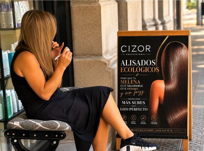 A photographer captures perfectly timed coincidences in Barcelona: a woman with long hair next to a hair product ad.