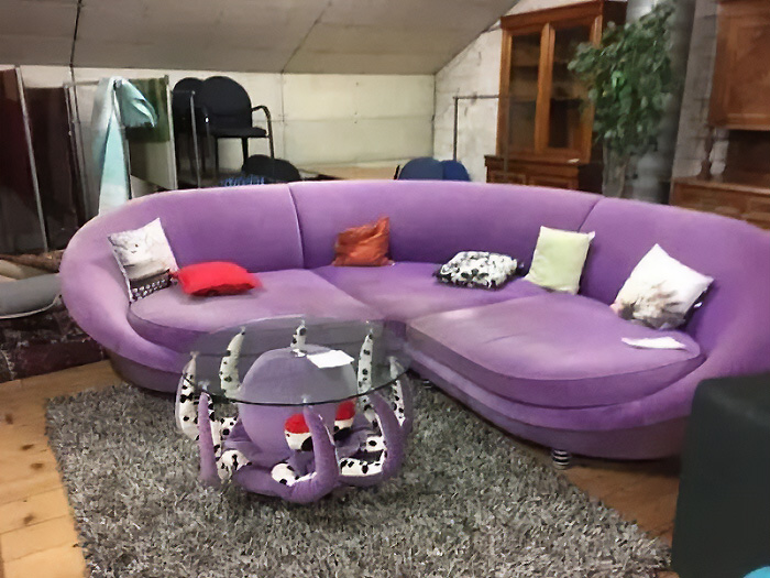 A unique purple curved sofa with an octopus-shaped coffee table, showcasing bizarre furniture design.