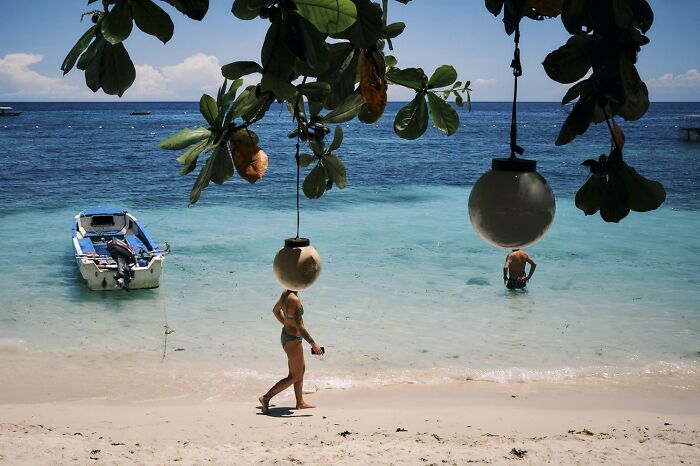 A woman walks on a beach with a perfectly timed street photo, capturing extraordinary moments in everyday life.