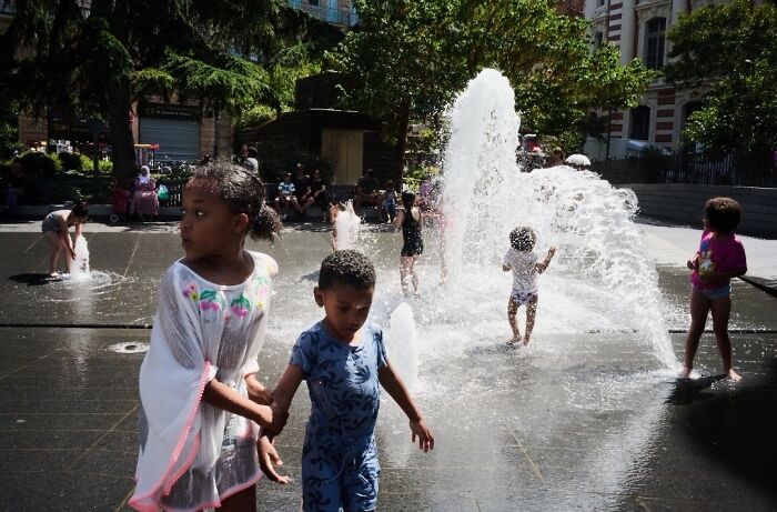 Children play in a public fountain on a sunny day, a perfectly timed street photo revealing extraordinary moments.