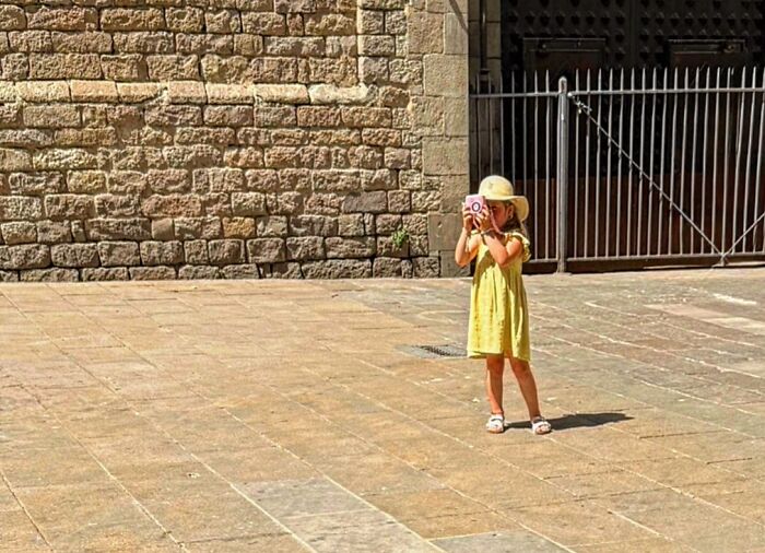 Photographer captures perfectly timed coincidences: a young girl with a hat takes a picture on the streets of Barcelona.