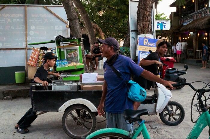 A man pushes a street cart with perfectly timed street photos revealing extraordinary moments in everyday life.