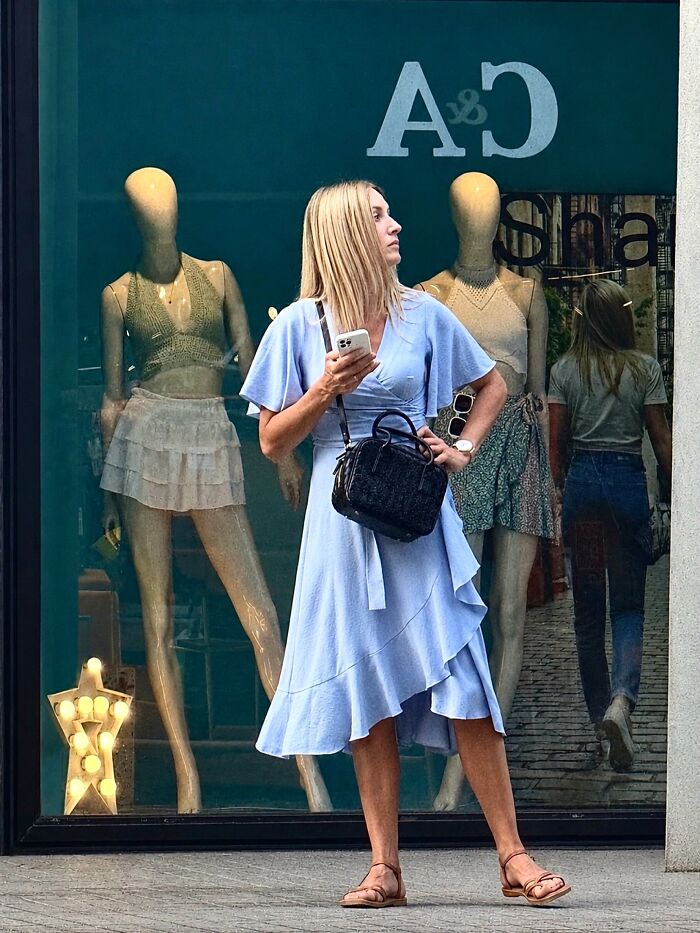 Photographer captures perfectly timed coincidences: a woman stands in front of a window, mirroring a mannequin, on the streets of Barcelona.