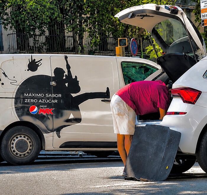 A photographer captures perfectly timed coincidences of a man bending over, aligning with a guitar player on a van in Barcelona.