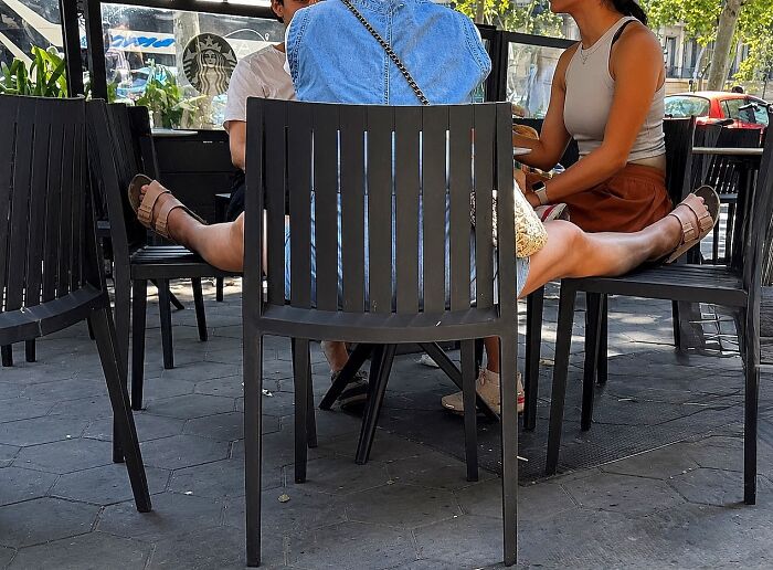 A photographer captures perfectly timed coincidences of two people sitting at an outdoor cafe with widely spread legs in Barcelona.