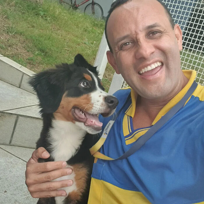 A smiling mailman holding a happy puppy, highlighting his heartwarming interactions with dogs on his delivery route.