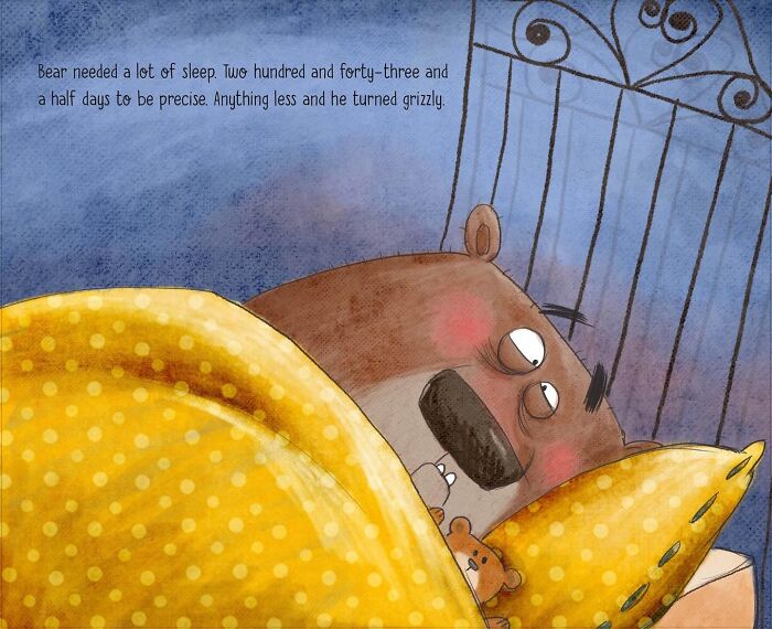 Illustrated character bear sleeping in a bed under a yellow polka-dotted blanket, with a small teddy bear next to him.