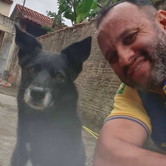 Close-up selfie of a kind mailman and a black dog, showing their friendly bond during deliveries.