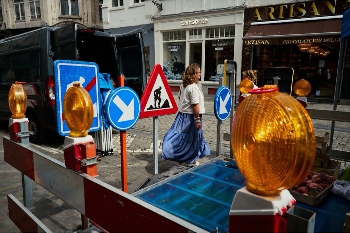 Perfectly timed street photo capturing a woman walking past construction signs, revealing an extraordinary moment in everyday life.