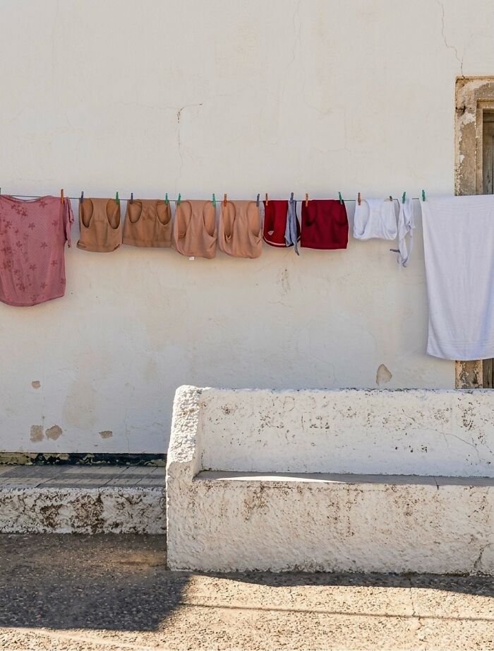 Clothes drying on a line in front of a white wall and concrete bench, capturing perfectly timed coincidences.