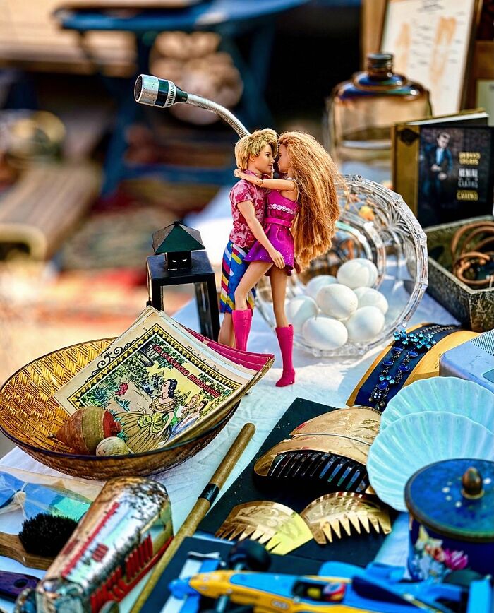 Two Barbie dolls hugging, with one having a telescope attached to her head, creating perfectly timed coincidences.