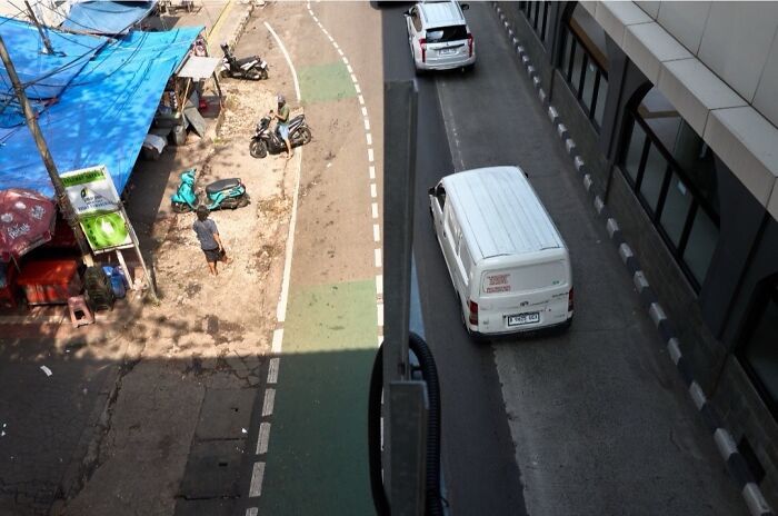 Perfectly timed street photo from above showing a bustling street with cars and motorbikes, an extraordinary moment.