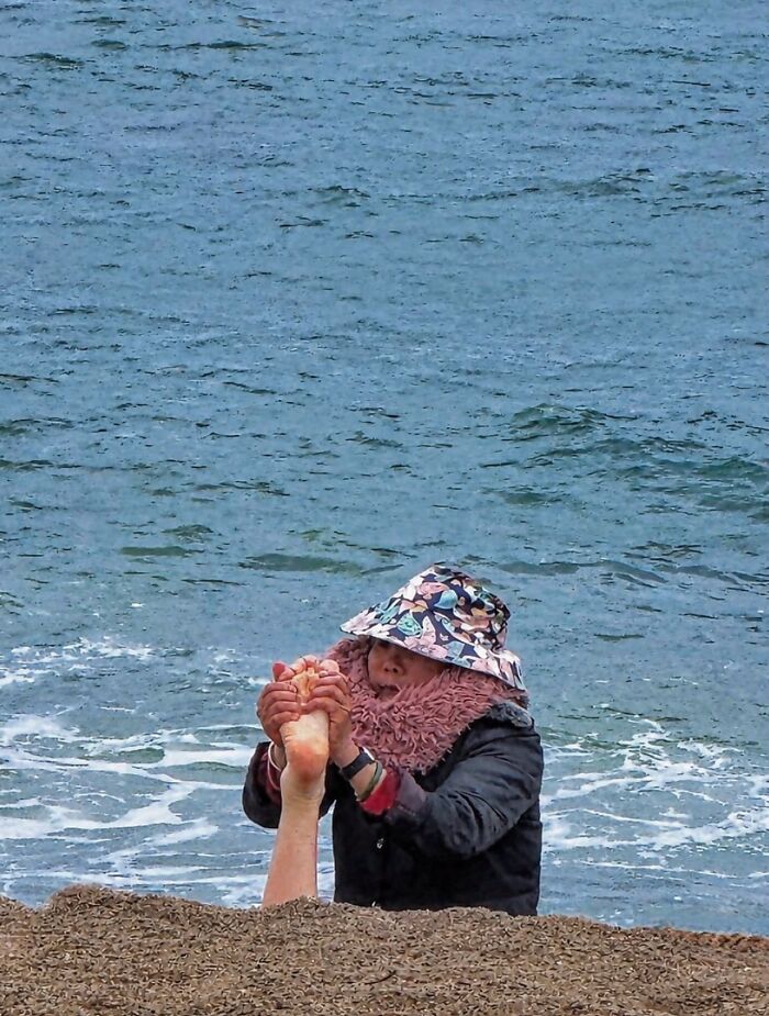 Photographer captures a perfectly timed coincidence of a person appearing to hold a leg emerging from the Barcelona sea.