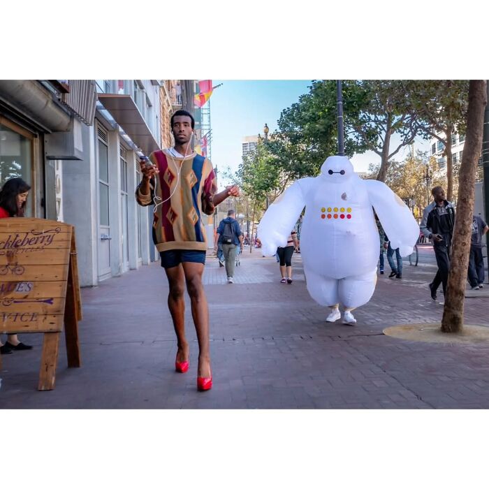 Photographer captures humor and chaos in everyday life, showing a person in red heels next to an inflatable Baymax costume.