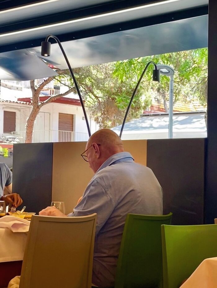Photographer captures a perfectly timed coincidence of a man at a table appearing to have antennae from light fixtures in Barcelona.