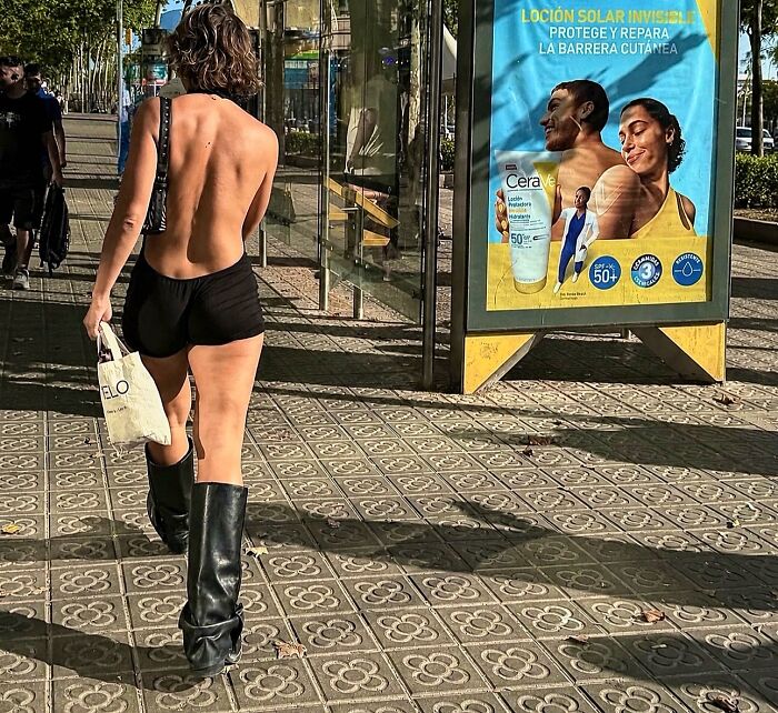 Woman walking in a street in Barcelona, her bare back mirroring the posture of the person in the ad, a perfectly timed coincidence.