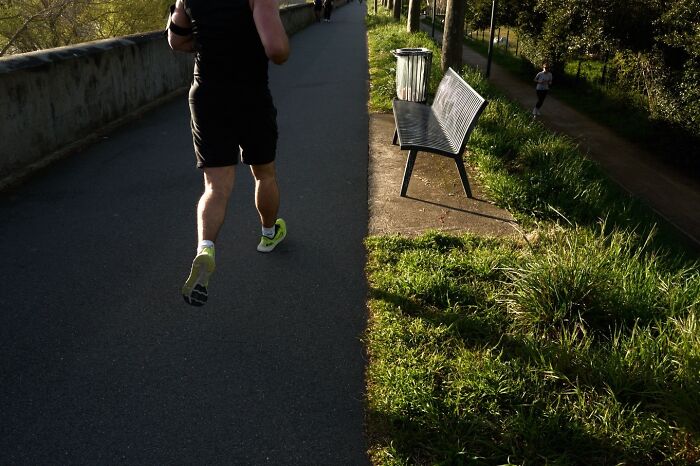 A perfectly timed street photo of a runner on a path, half in sun and half in shadow.
