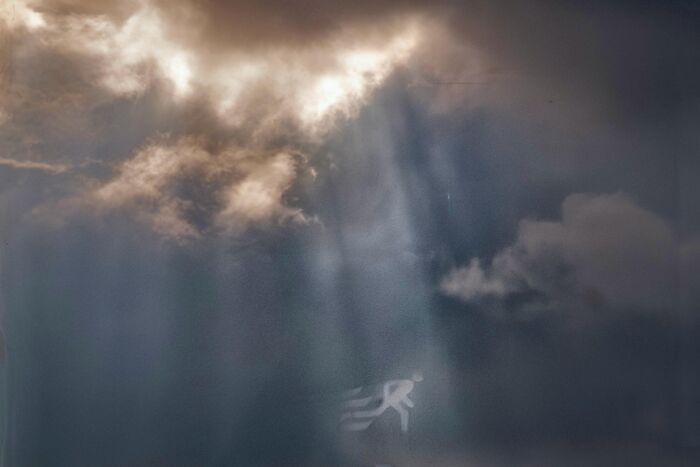 Street coincidences caught on camera: A heavenly light shining on a pedestrian walking sign, creating an angelic silhouette.