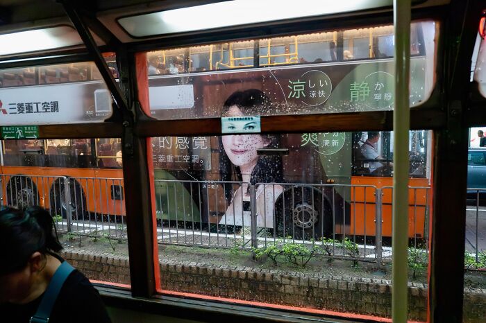 Street coincidences caught on camera: A bus advertisement of a woman's face perfectly aligns with the view from a tram.