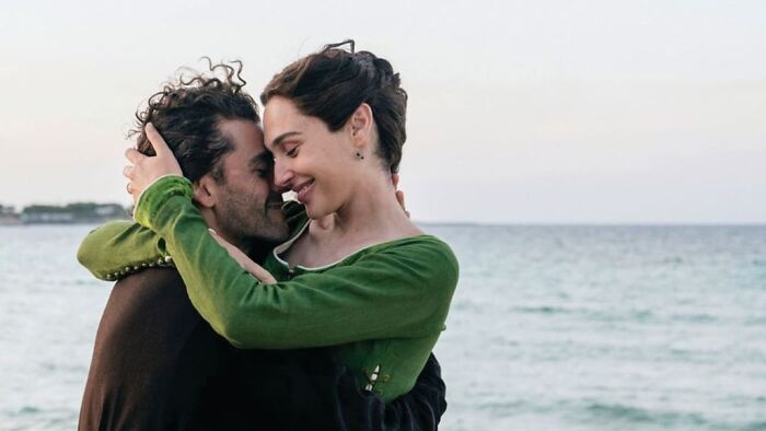 Gal Gadot embraces a man, both smiling, with the sea in the background from her new Netflix film.